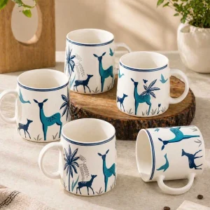 Set of 2 aesthetic ceramic mugs with blue deer print design placed on a wooden base in a cozy minimal setup